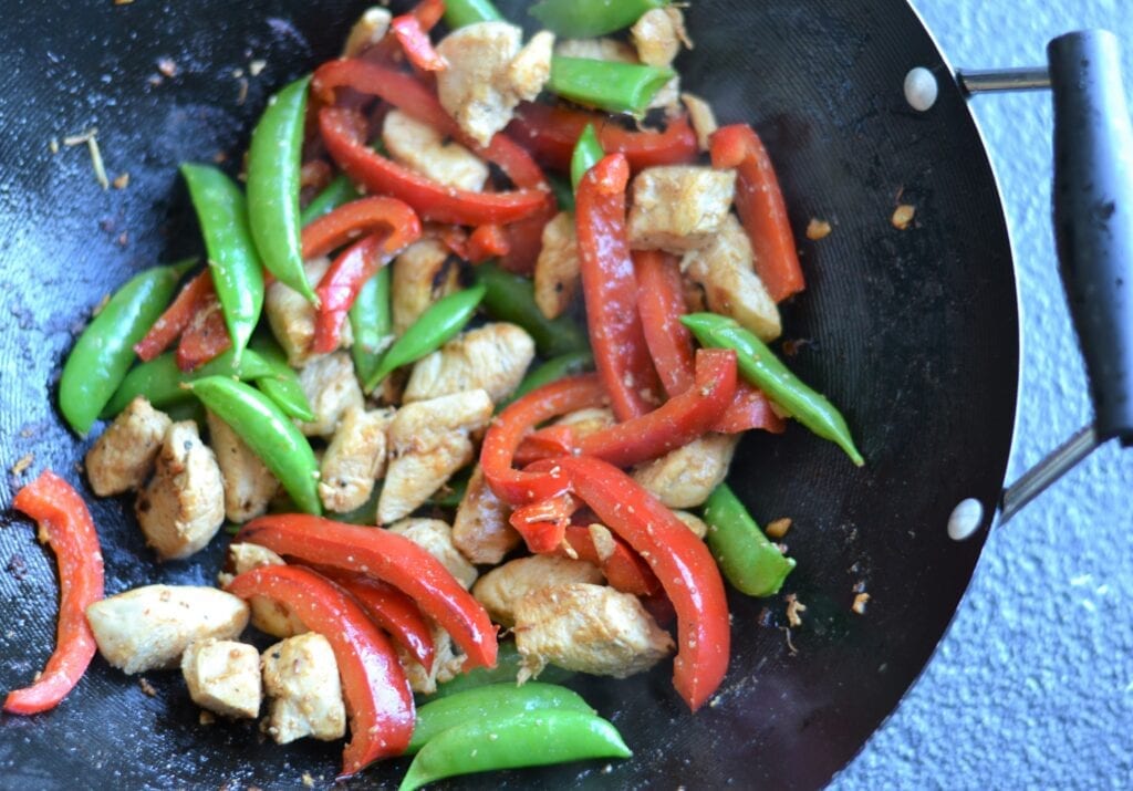 Wok with chicken, red peppers, and snap peas.