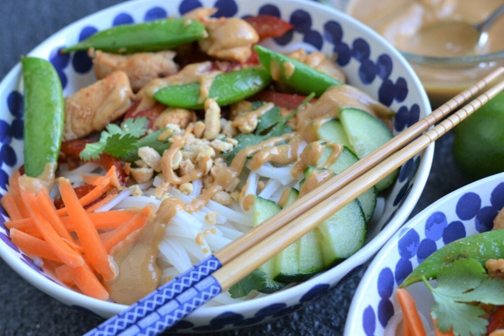 A bowl with sesame chicken noodles. 