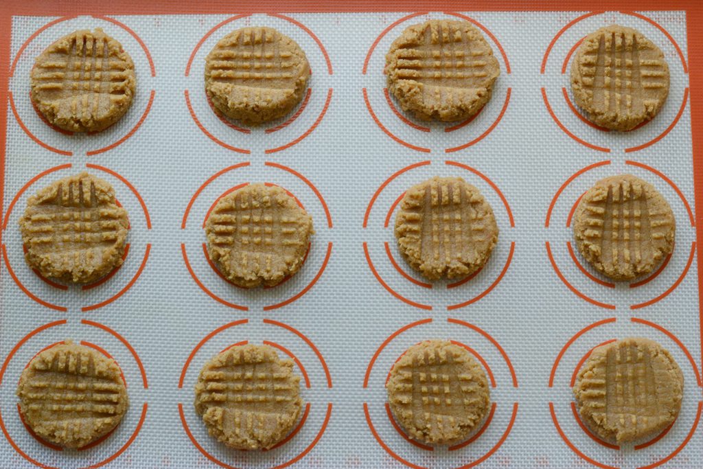 Almond Flour Peanut Butter Cookies on a cookie sheet with a baking mat