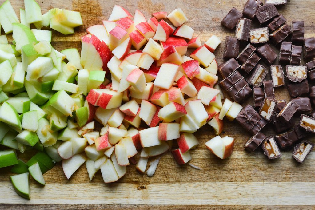 chopped apples and snickers on a cutting board