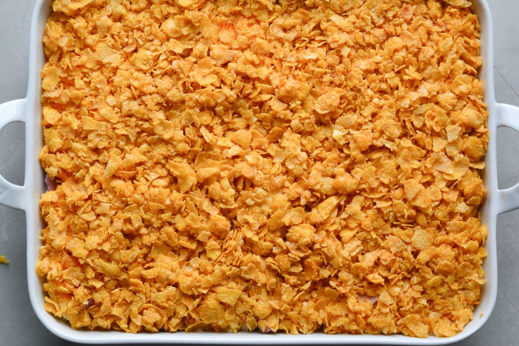baking dish with layered hashbrowns, ham, and cheese with cornflake topping