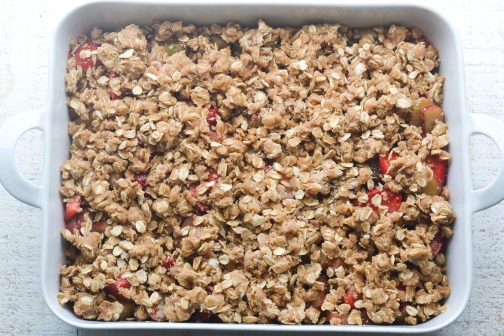 strawberry and rhubarb mixture with oat topping in the baking dish